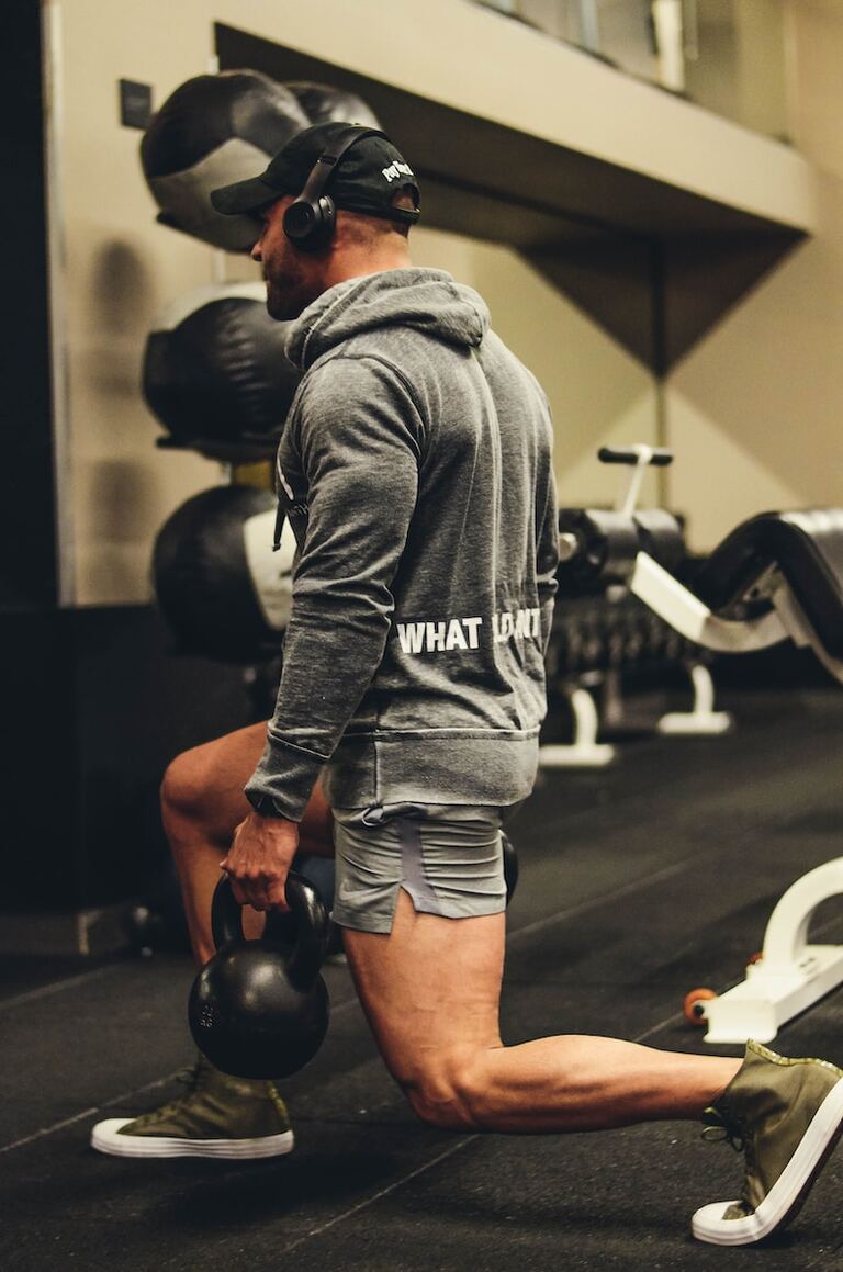 man in gray hoodie and blue denim shorts standing on black and white exercise equipment